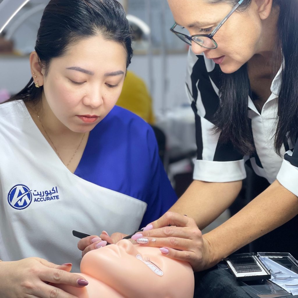 Instructor teaching eyelash extension technique to students during hands-on training