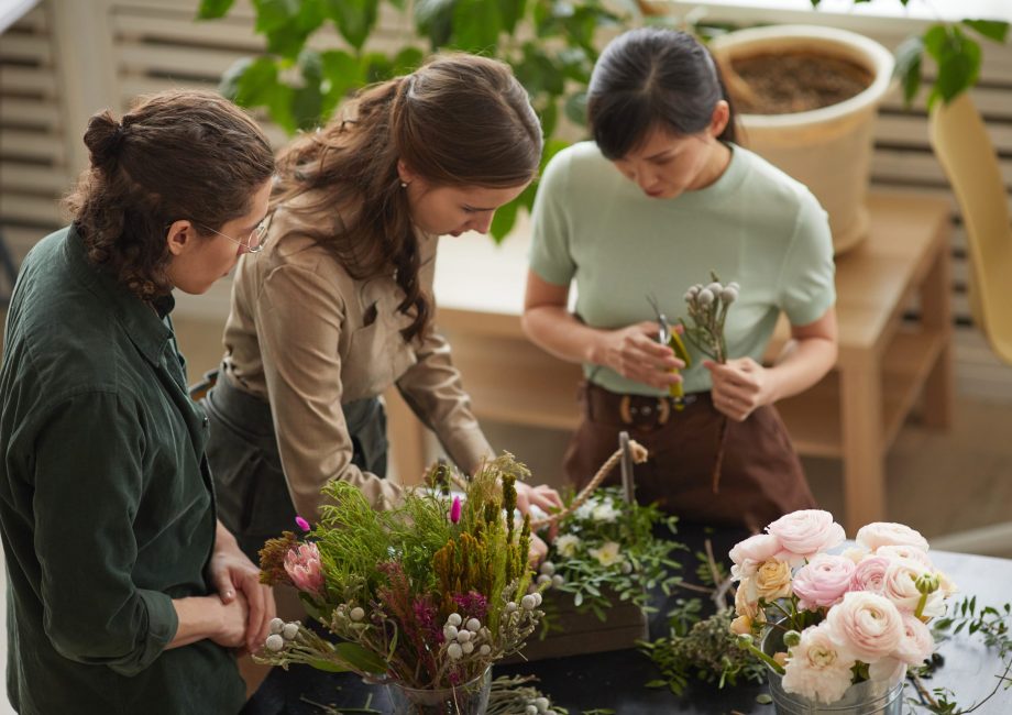 High angle view at group of florists arranging floral compositions in workshop, copy space