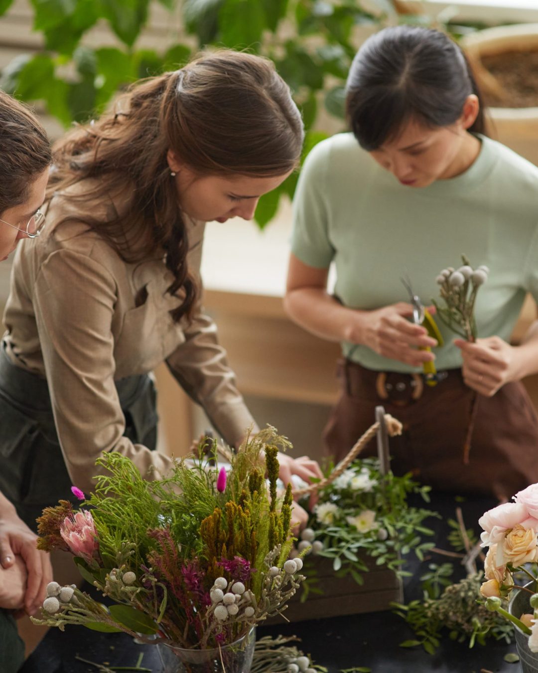 High angle view at group of florists arranging floral compositions in workshop, copy space