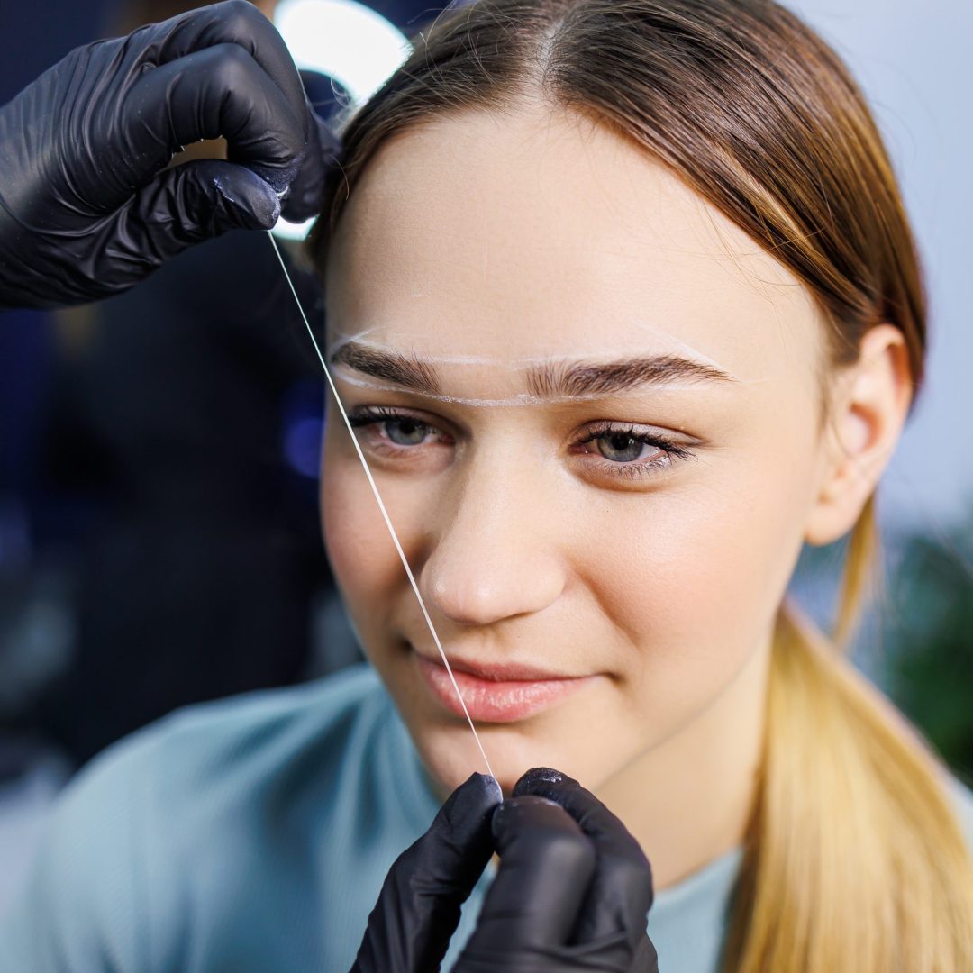 Marking a woman's face before a permanent eyebrow tattoo procedure. Women's master of permanent make-up